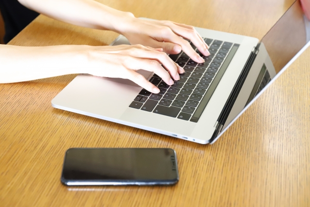 woman-hands-typing-laptop-smartphone