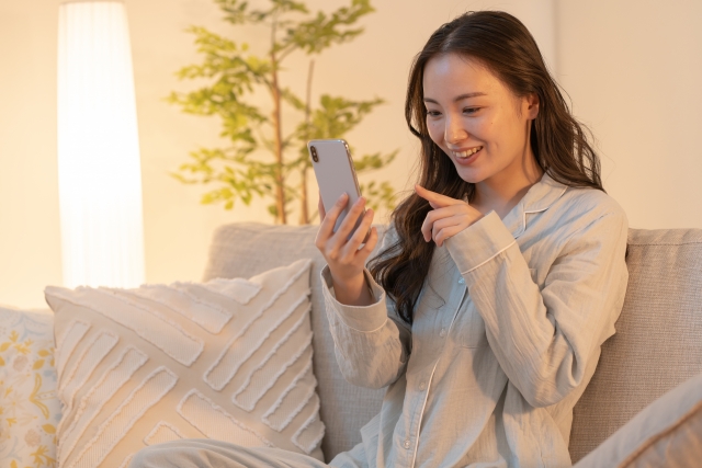woman-smiling-smartphone-sofa-pajamas