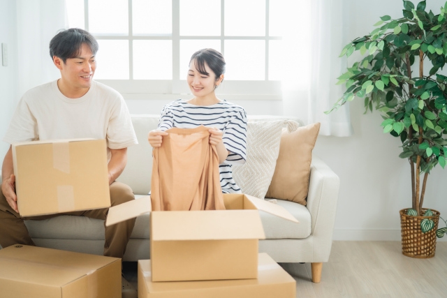 若いカップル_引越しの荷解き_段ボールと新居リビング