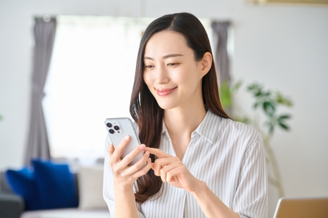 女性_スマホを操作_リビング_笑顔