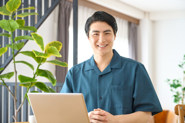 男性_ノートPC前で笑顔_観葉植物