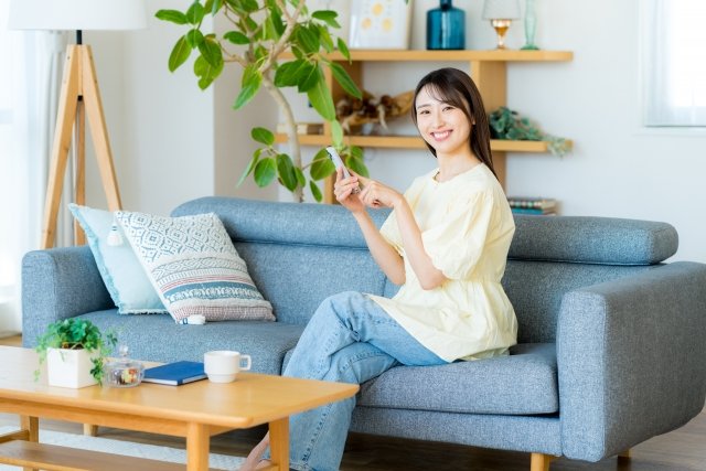 woman-smiling-holding-smartphone-sofa